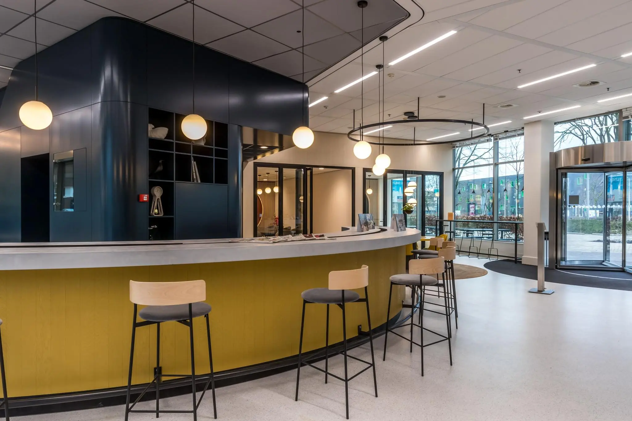 Moderne en licht ingerichte ontvangsthal met ronde balie en barkrukken aan de Vliegend Hertlaan.